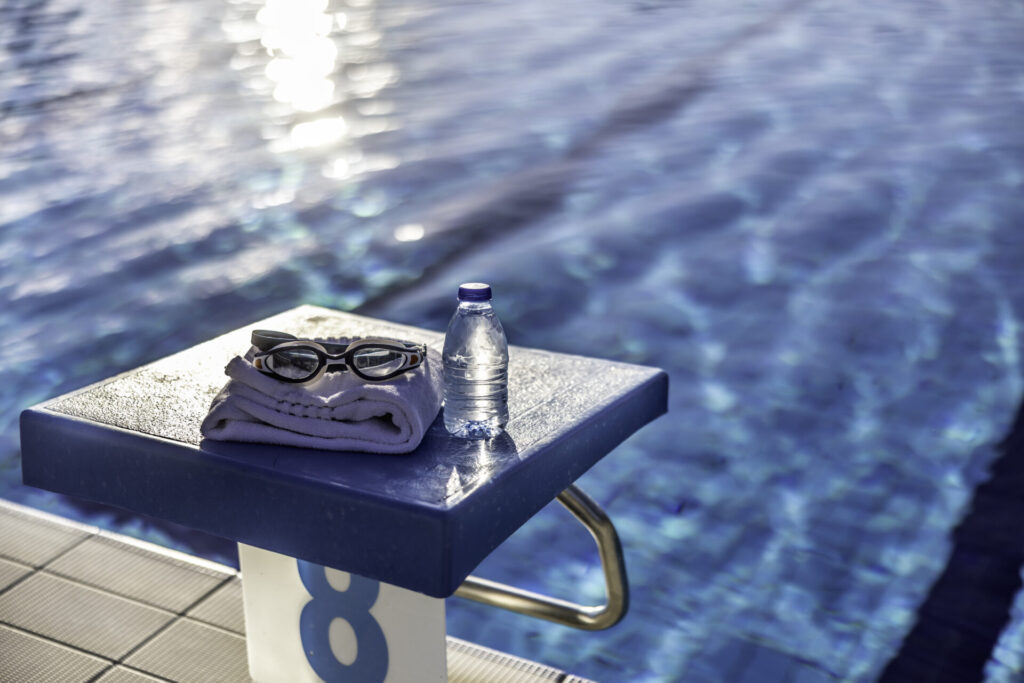 Swimming goggles and a towel placed on the starting bridge by the swimming pool.